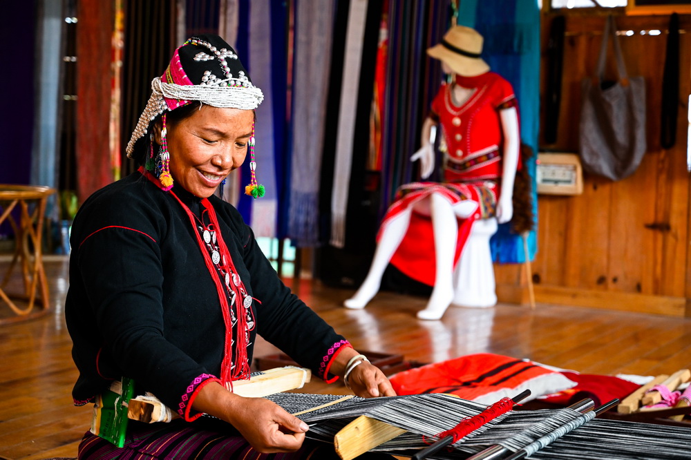 12月20日，秧洛村村民在西盟印象民族文化有限公司内制作织锦。